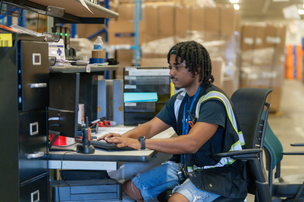 Porter Logistics employee typing on computer in storage warehouse